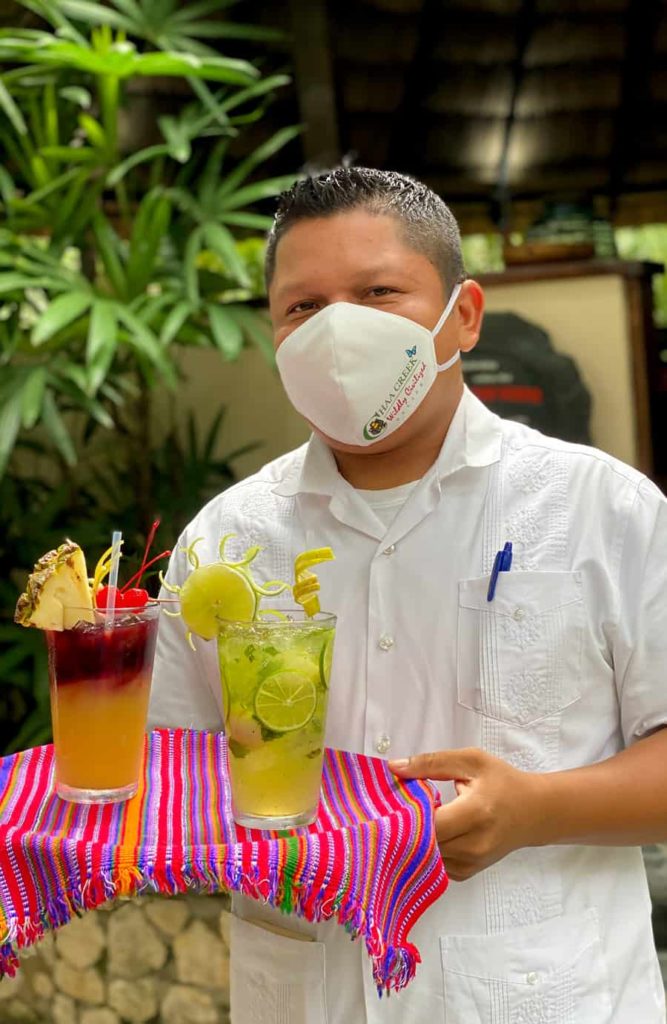 chaa creek bartender with cocktails and face mask on